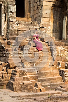 Cambodian Girl in Khmer Dress Sitting at Bayon Temple in Angkor City
