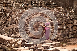 Cambodian Girl in Khmer Dress Standing by Ruins of Bayon Temple in Angkor City