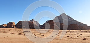 Camel caravan with tourists goes through the Wadi Rum desert in Jordan