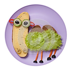 Camel created from black bread, cheese and vegetables on plate