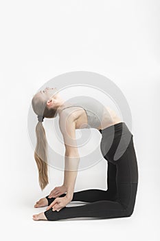 Camel Pose. Ustrasana. Young attractive woman practicing yoga on white background. Slender girl is engaged in gymnastics