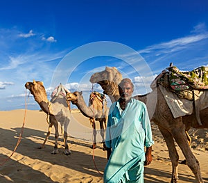 Cameleer (camel driver) with camels in dunes of Thar desert. Raj