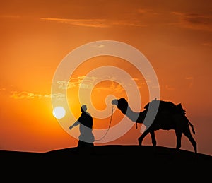 Cameleer (camel driver) with camels in dunes of Thar desert. Raj