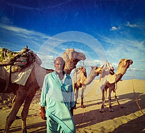 Cameleer camel driver with camels in dunes of Thar desert. Raj