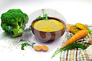 Camelina sativa flour in ceramic bowl, cookies, carrot and broccoli isolated on white background