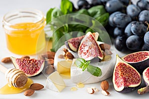 Camembert or Brie cheese platter with grapes, figs and honey