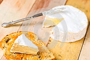 Camembert cheese with cut wedge on toasted bread slice and vinta