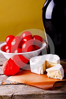 Camembert cheese in front of wine and tomatoes