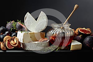 Camembert cheese with fruits and honey on a black background