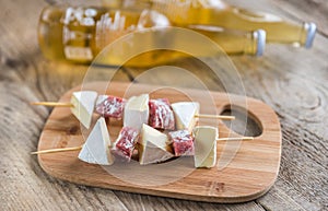 Camembert and salami skewers with bottles of beer photo