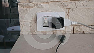 Camera come close to an electric plug and multi outlets faster at home with yellow stone brick wall - european sockets
