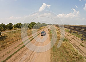 The camera on the drone tracks the car that drives on a bad road