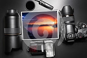 Camera equipment around a printed photo about a sunset on the sea.