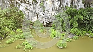 Camera Flies over Large Lake to Cave in Steep Cliff