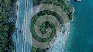 The camera flies over the road located on the seashore in the evening.