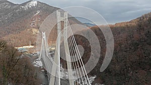 camera is flying over modern cable-stayed bridge in mountain area, aerial view