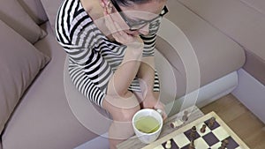Camera focuses on chessboard then on woman chess player