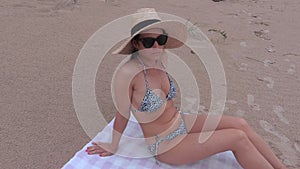 Camera focusing on flip flops and woman in straw hat on beach