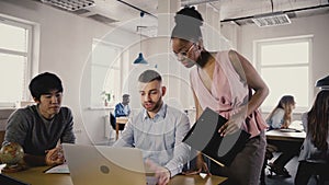 Camera follows African American woman boss enter office, give directions to workers. Multiethnic group teamwork 4K.