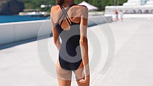 Camera follows Beautiful confident shapely woman in black swimwear