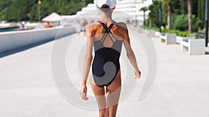 Camera follows Beautiful confident shapely woman in black swimwear