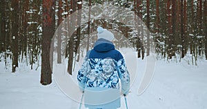 The camera follows an elderly female skier in a blue suit