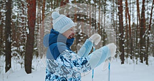 The camera follows an elderly woman riding classic skis through a winter forest