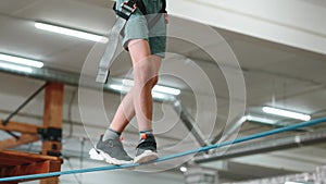 The camera follows the feet of a little boy who is walking on a thin rope