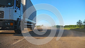 Camera follows to truck with cargo trailer driving on highway transporting goods at sunny day. White truck riding