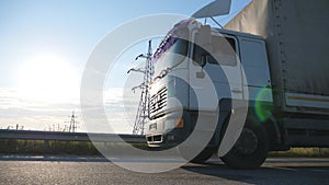 Camera follows to truck on a highway. Lorry speeding through the countryside with sunset at background. Bottom Side view