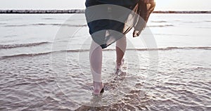 Camera follows young beautiful back lit woman in summer dress walk along epic calm sunrise sea beach water slow motion.