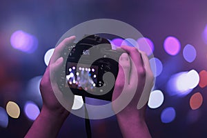 Camera in hands. Bokeh and concert, live music lights in background