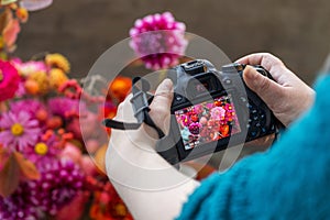 Camera on hands closeup. Making nature photo and video with autumn flowers