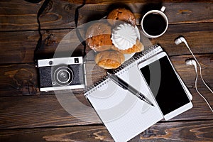 Camera with headphones with croissants and coffee next to notebook