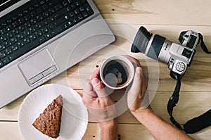 Camera and laptop on wooden background. Coffee and cake.