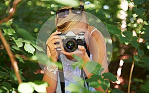 Camera lens, shooting and photographer with woman in forest for relax, memory and travel photography. Summer, trees and