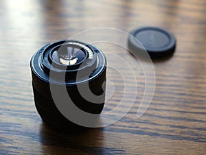 Camera lens sitting on wooden desk in sunlight.