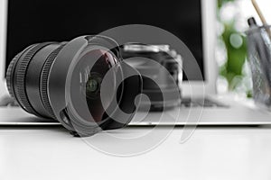 Camera lenses and laptop on white table