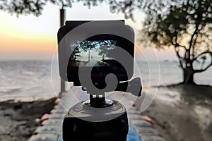 Camera mounted on a tripod photograph the pier and sunrise. Close up, view on screen