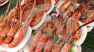 Camera movement of roast and charcoal grill of cooked lobsters in a plastic plate. It is a traditional Thai seafood recipe