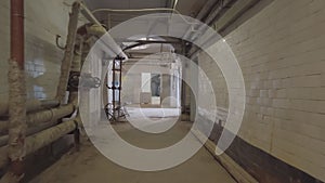 Camera moves along the basement corridor , along the walls are pipes and communications