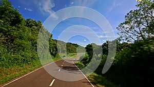 Camera Moves along Curvy Country Road among Hilly Landscape