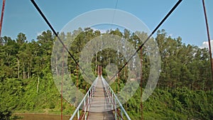 Camera Moves along Suspension Bridge over River in Park