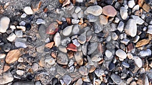 The camera moves in a circular motion around the axis over the pebble beach with beautiful pebble stones on the seashore. Recreati