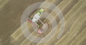 Camera moves down to thresher pouring cereal into lorry