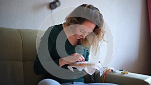 the camera moves next to a girl embroidering a picture on the canvas