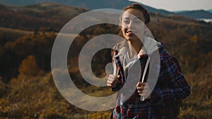 Camera moving around hipster millennial young woman standing on top of mountain summit at sunrise, looking ahead