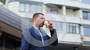 Camera moving around young handsome male standing outdoors drinking coffee. Close up portrait of Caucasian successful