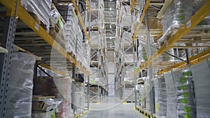 Camera moving through warehouse. racks with merchandise. rows shelves with cardboard products