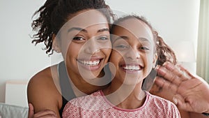 Camera pov portrait of young african american mother and daughter recording selfie video, smiling to cam, slow motion